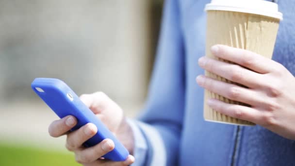 Mulher sorridente com xícara de café e smartphone — Vídeo de Stock