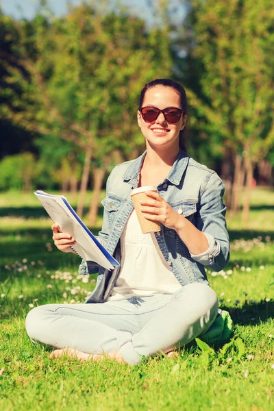 Lächelndes junges Mädchen mit Notizbuch und Kaffeetasse — Stockfoto