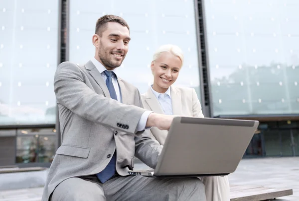 Smiling businesspeople with laptop outdoors — Stock Photo, Image