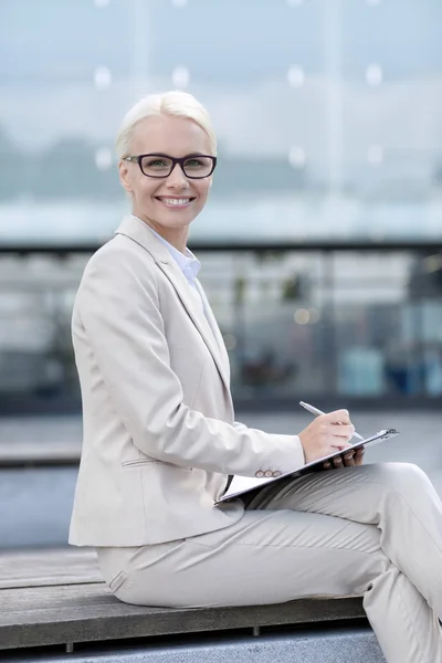 Joven mujer de negocios sonriente con bloc de notas al aire libre — Foto de Stock