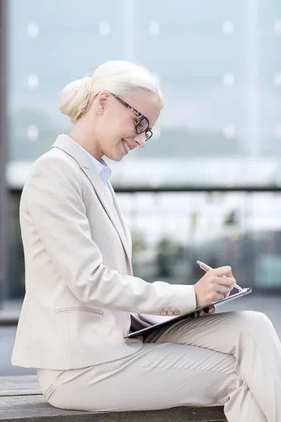 Young smiling businesswoman with notepad outdoors — Stock Photo, Image