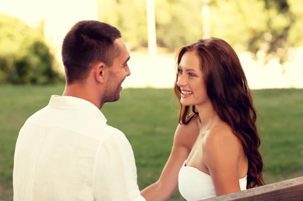 Couple souriant assis sur le banc dans le parc — Photo