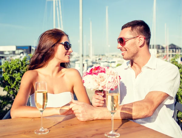 Sonriente pareja con racimo y champán en la cafetería —  Fotos de Stock