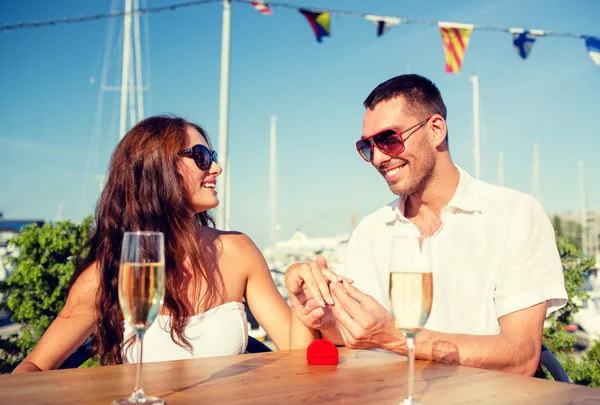 Pareja sonriente con champán y regalo en la cafetería —  Fotos de Stock