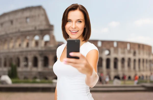 Woman taking selfie with smartphone over coliseum — Stockfoto