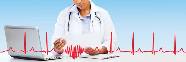 Femme médecin avec ordinateur portable PC regardant le papier — Photo