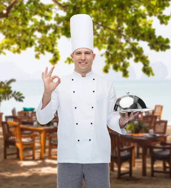 Cozinheiro chef macho feliz com cloche mostrando sinal ok — Fotografia de Stock