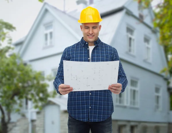 Smiling builder with blueprint over house — Stock Photo, Image