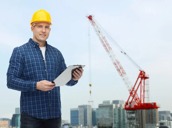 Lächelnder männlicher Bauarbeiter im Helm mit Klemmbrett — Stockfoto