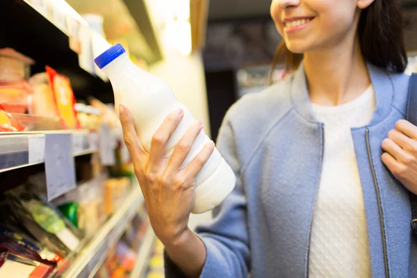 Szczęśliwa kobieta trzymając butelkę mleka w rynku — Zdjęcie stockowe