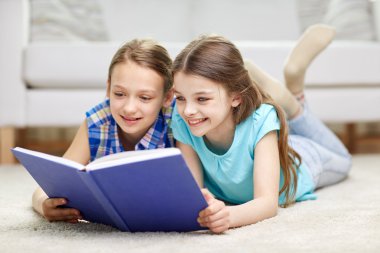 two happy girls reading book at home clipart