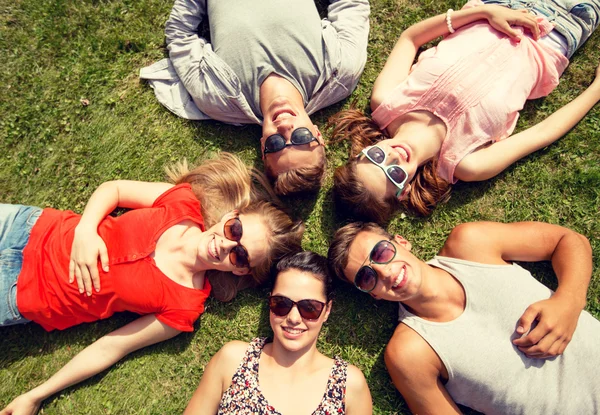 Grupp av leende vänner ligger på gräs utomhus — Stockfoto