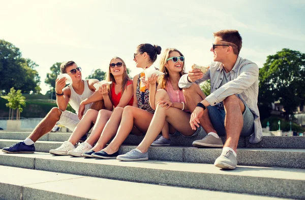 Groep lachende vrienden zitten op het stadsplein — Stockfoto