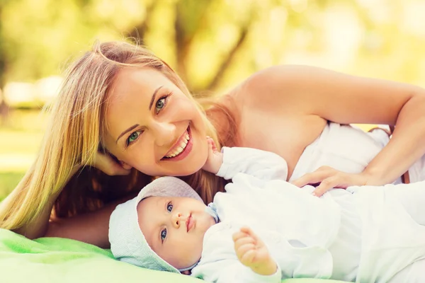 Feliz madre acostada con un pequeño bebé sobre una manta — Foto de Stock