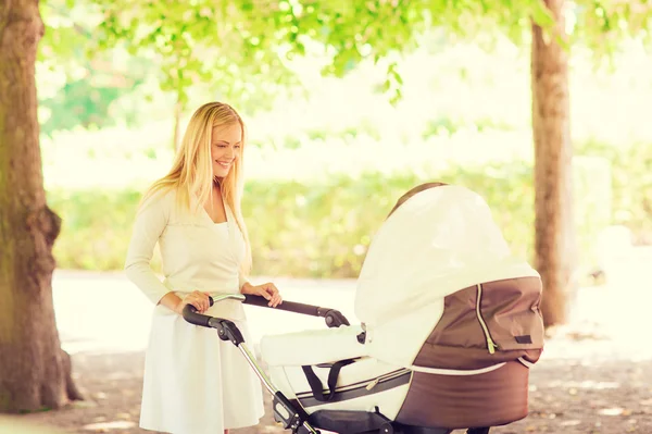 Glad mamma med barnvagn i park — Stockfoto