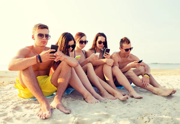 Grupo de amigos con smartphones en la playa —  Fotos de Stock