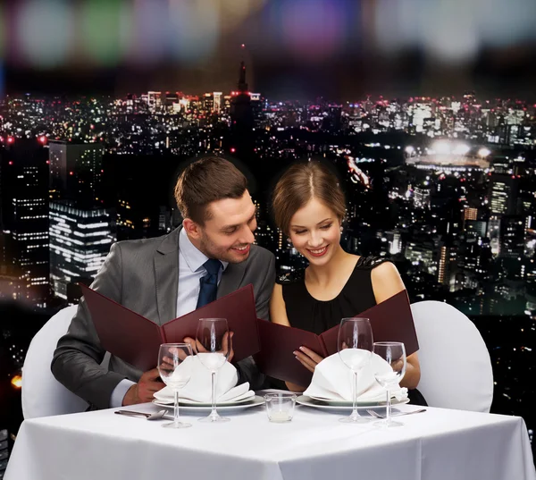 Concept de restaurant, de couple et de vacances - souriant couple avec menus au restaurant — Zdjęcie stockowe