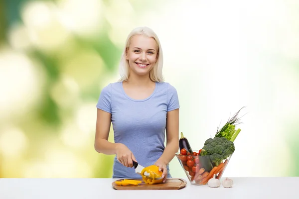 Sorridente giovane donna che taglia le verdure a casa — Foto Stock