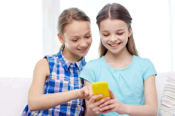 happy girls with smartphone sitting on sofa