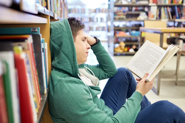 Studente ragazzo o giovane lettura libro in biblioteca — Foto Stock