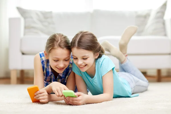 Chicas felices con teléfonos inteligentes tumbados en el suelo —  Fotos de Stock