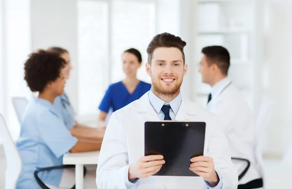 Médico feliz com tablet pc sobre a equipe na clínica — Fotografia de Stock