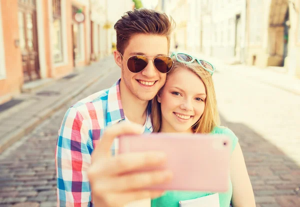 Casal sorridente com smartphone na cidade — Fotografia de Stock