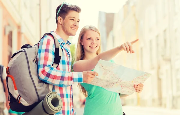 Smiling couple with map and backpack in city — Stock Photo, Image