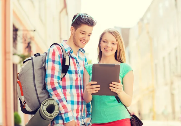 Smiling couple with tablet pc and backpack in city — Stock Photo, Image