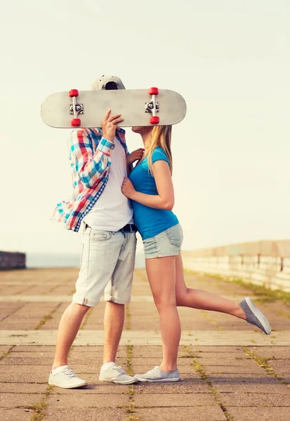 Couple with skateboard kissing outdoors — Stock Photo, Image