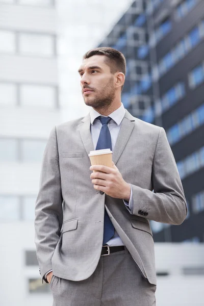 Joven hombre de negocios serio con taza de papel al aire libre — Foto de Stock