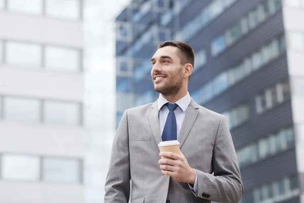 Jeune entrepreneur souriant avec extérieur de tasse de papier — Stock fotografie