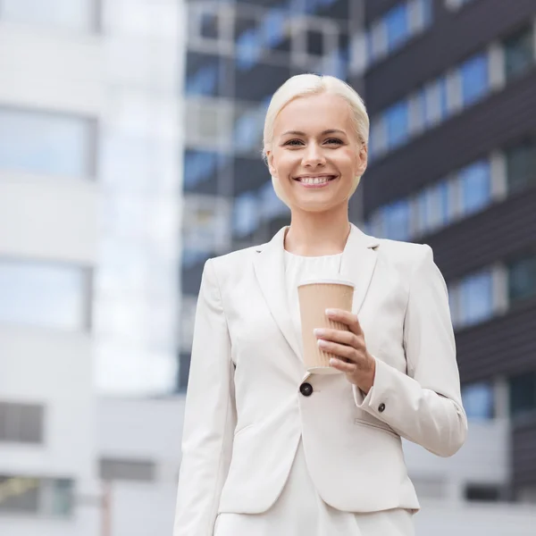 Femme d'affaires souriante avec tasse en papier à l'extérieur — Photo