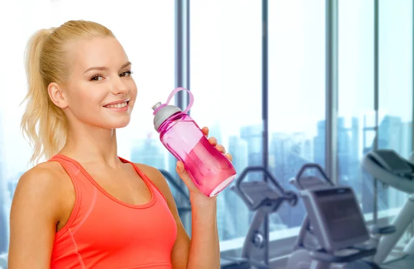 Mujer feliz beber agua de la botella en el gimnasio —  Fotos de Stock