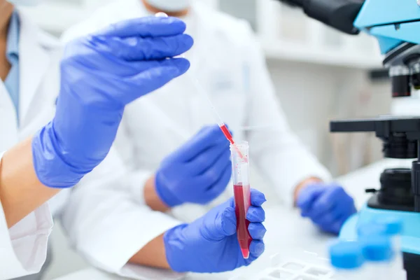 Primer plano de los científicos que llenan el tubo de ensayo en laboratorio — Foto de Stock