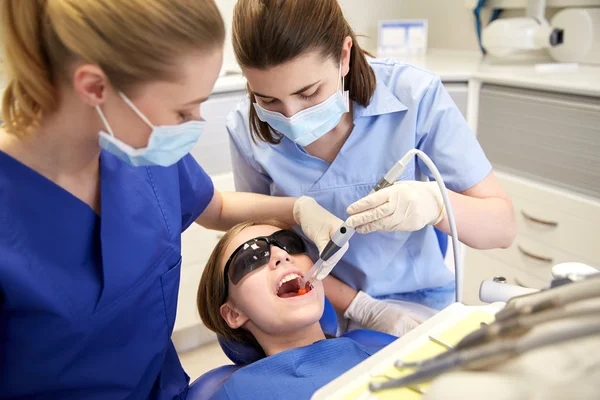 Female dentists treating patient girl teeth — Stock Photo, Image