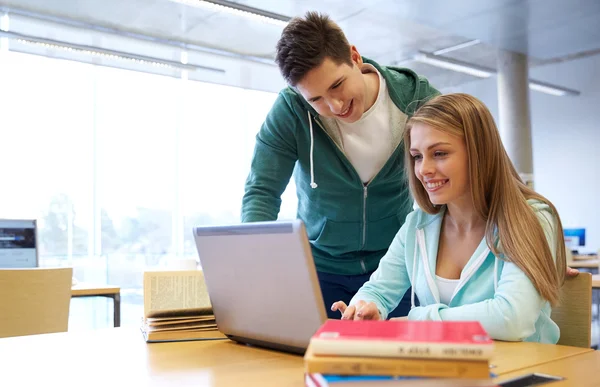 Glada studenter med laptop i biblioteket — Stockfoto