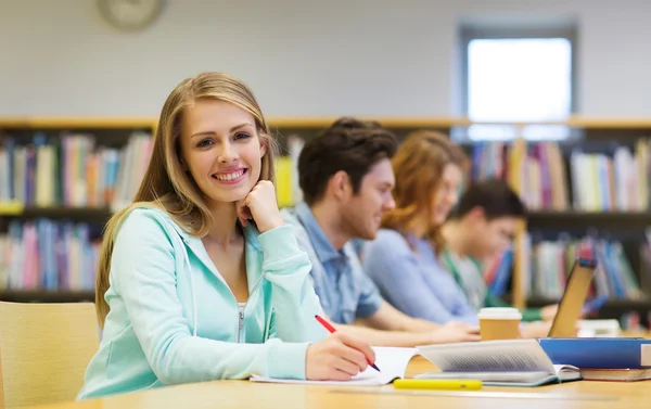 Glückliches Studentenmädchen schreibt in Bibliothek an Notizbuch — Stockfoto