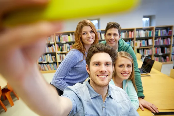 Studenti con smartphone scattare selfie in biblioteca — Foto Stock