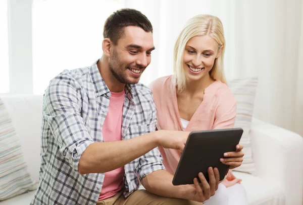 Sorridente coppia felice con tablet pc a casa — Foto Stock