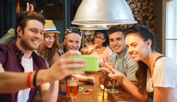 Amigos felizes com smartphone tomando selfie no bar — Fotografia de Stock