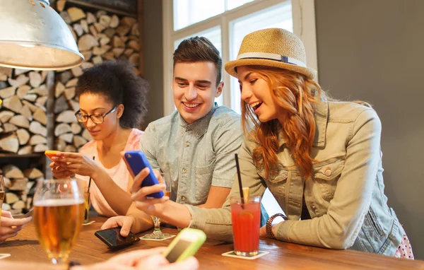 Amis heureux avec smartphones et boissons au bar — Photo