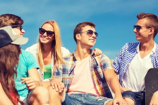 Group of smiling friends sitting on city street — Stock Photo, Image