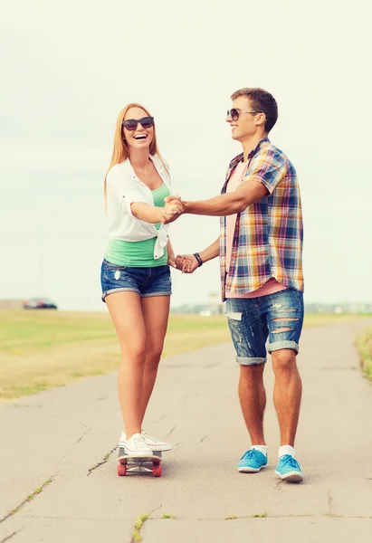 Lachende paar met skateboard buitenshuis — Stockfoto