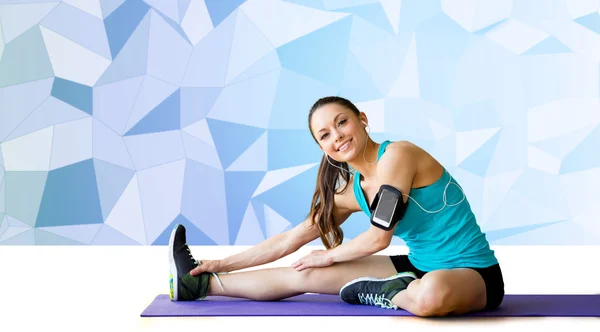Smiling woman stretching leg on mat over low poly — Stock Photo, Image