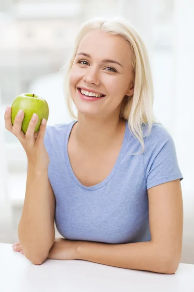 Mulher feliz comer maçã verde em casa — Fotografia de Stock