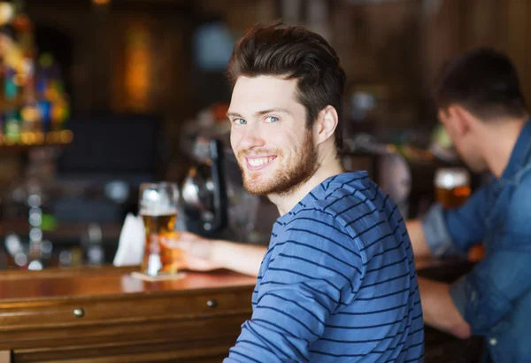 Jovem feliz bebendo cerveja no bar ou pub — Fotografia de Stock