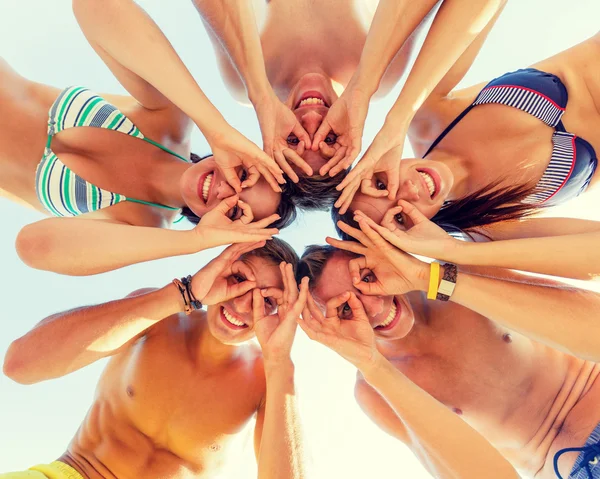 Lächelnde Freunde im Kreis am Sommerstrand — Stockfoto