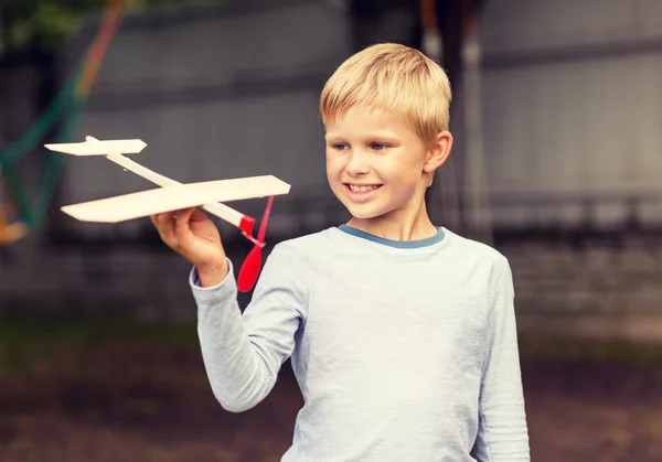 Smiling little boy holding a wooden airplane model — Stock Photo, Image