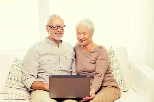 Feliz pareja de ancianos con portátil en casa — Foto de Stock